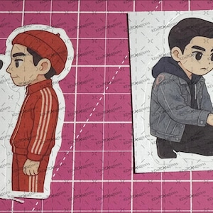Peut inclure: Deux ensembles d'autocollants représentant des personnages de dessins animés. Le premier ensemble montre deux garçons debout côte à côte. Un garçon porte une veste rouge et l'autre une veste noire. Le deuxième ensemble montre deux garçons assis. Un garçon porte une veste bleue et l'autre une chemise à carreaux bleu et blanc.
