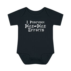 May include: Dark navy blue baby bodysuit with the text "I PERFORM WAH-WAH EFFECTS" in white, stylized font. The short-sleeved onesie is made of soft fabric and is designed for infants. A fun and playful garment.
