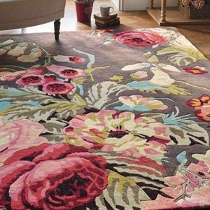 May include: A brown rug with a floral pattern featuring large pink, red, and yellow flowers. The rug has a textured, hand-woven look.