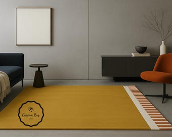 May include: Mustard yellow rectangular rug with a white and orange striped border. The rug is in a modern living room setting with a dark blue sofa, orange chair, and a framed artwork on the wall.