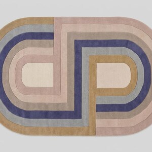 Studio top-down of modern oval area rug, bold abstract interlocking arch pattern in lavender, mauve, tan
