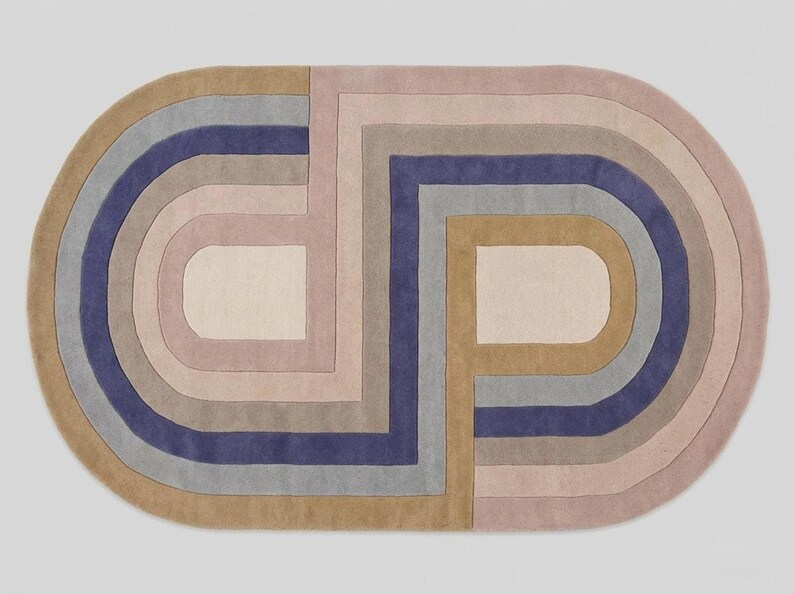 Studio top-down of modern oval area rug, bold abstract interlocking arch pattern in lavender, mauve, tan