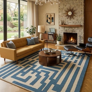May include: A mid-century modern living room with a mustard yellow sofa, a blue and white geometric rug, and a stone fireplace. A round wooden coffee table sits in the center, and a large window offers a view of the outdoors. A sputnik chandelier hangs from the ceiling.