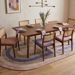 Dining table set on modern oval area rug, hand carved relief arches in lavender, tan, and mauve tones