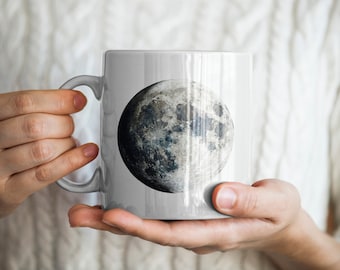May include: White ceramic mug with a full moon image printed on it. The moon is gray and white with craters and shadows.