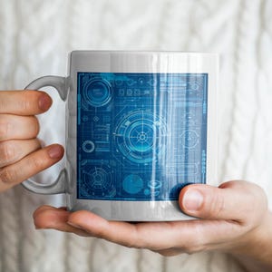May include: A white ceramic mug with a blue and white design of a futuristic circuit board. The mug is being held by a person's hands.