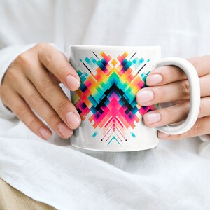 May include: A white ceramic mug with a colorful geometric design featuring squares and lines in shades of pink, blue, yellow, green, and black.