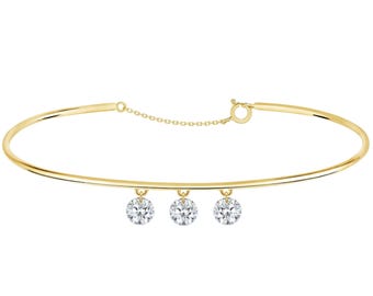 Op de afbeelding: Een goudkleurige armband met drie ronde, heldere edelstenen die in het midden hangen. De armband heeft een eenvoudig, elegant ontwerp met een sluiting en een fijne ketting. De edelstenen zijn gelijkmatig verdeeld.