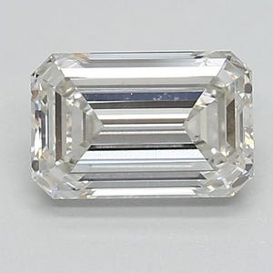 May include: A clear, emerald-cut diamond. The rectangular gemstone features step-cut facets, creating a brilliant display of light. The diamond's clarity is high, and it is set against a neutral background to enhance its sparkle and brilliance.