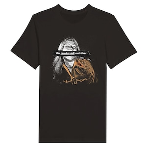 以下が含まれることがあります： 黒いTシャツに、口を黒い帯で覆われた女性のグラフィックがプリントされています。帯には「Her careless talk costs lives」という文字が書かれています。