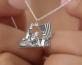May include: A silver necklace with a pendant featuring a photo of three people raising an American flag. The pendant is a detailed silhouette of the people and flag.