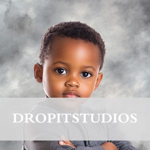Może przedstawiać: Młody chłopiec o krótkich, ciemnych włosach ma na sobie szarą koszulę z długim rękawem. Ma skrzyżowane ramiona i patrzy prosto w kamerę. Tło to szare, pochmurne tło z tekstem "DROPITSTUDIOS" na dole.