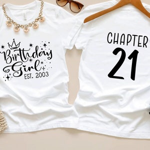 May include: Two white t-shirts, one with the text 'Birthday Girl Est. 2003' and a crown design, and the other with 'Chapter 21'.  The shirts are displayed with accessories including a brown hat, necklace, sunglasses, jeans, and leopard print shoes. The overall theme is a 21st birthday celebration.