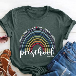 May include: A green t-shirt with a rainbow design and the words "preschool" and "Miss Angel".