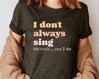 May include: A dark gray t-shirt with the text "I don't always sing Oh wait... yes I do" in colorful retro-style lettering.