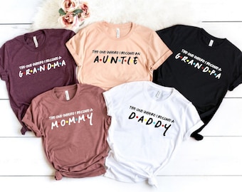 Peut inclure: Cinq t-shirts avec le texte "The One Where I Become A" suivi d'un mot différent sur chaque t-shirt. Les mots sont "Grandma", "Auntie", "Grandpa", "Mommy" et "Daddy". Chaque mot est stylisé pour ressembler au logo de la série Friends.