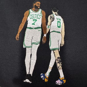 May include: Embroidered image of two basketball players in green and white Celtics jerseys. One player wears the number 7, the other number 0. The background is black.