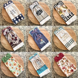 May include: Nine kitchen towels with different designs and sayings. The towels are folded and displayed on wooden cutting boards. The towels have a quilted backing and a loop for hanging. The sayings on the towels include "Gather Grateful Hearts", "Live Simply", "Blessed Thankful", "Everything is Better with Coffee", and more.