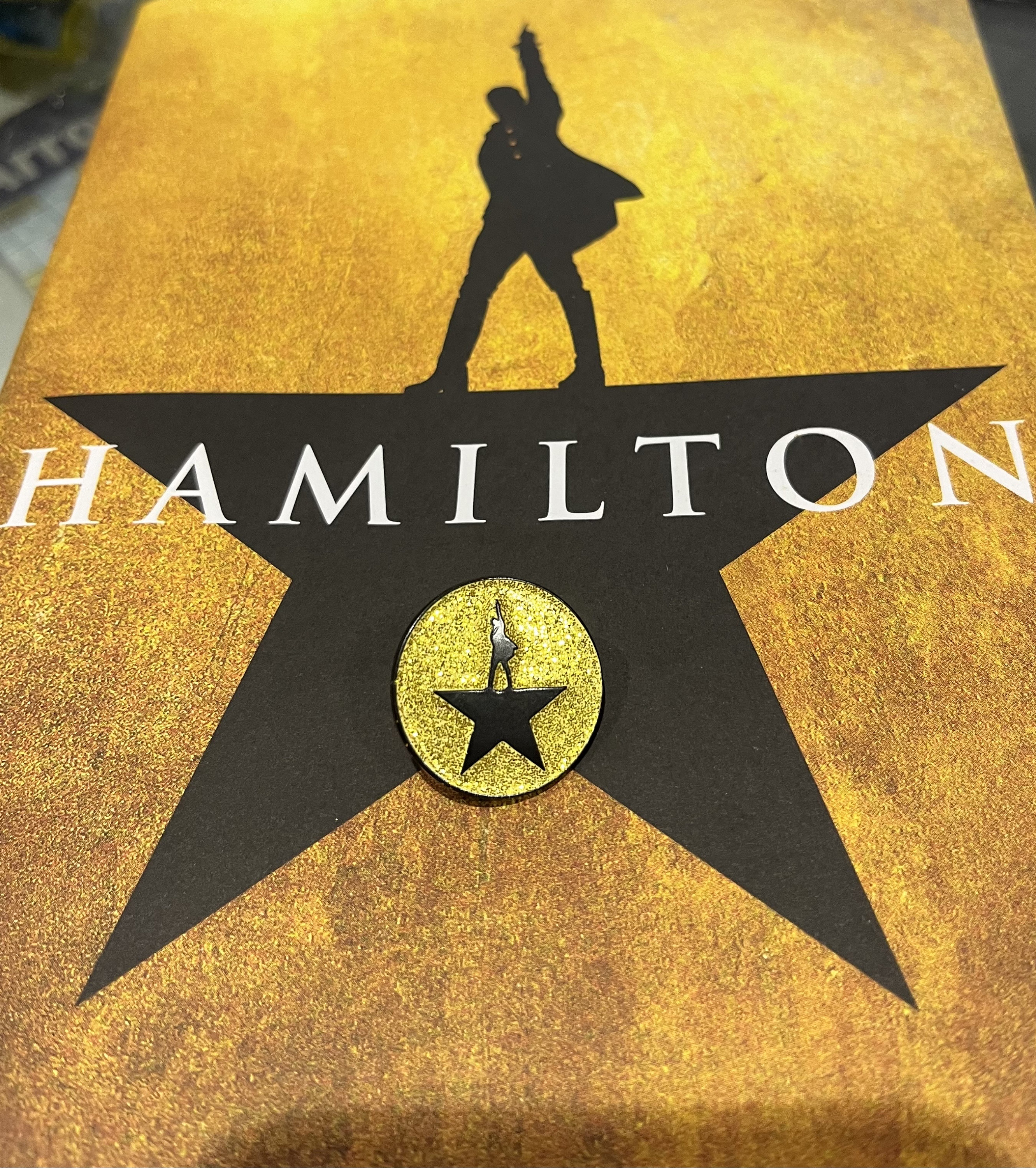 Insignia con logo dorado brillante de Hamilton the Musical: accesorio para fanáticos