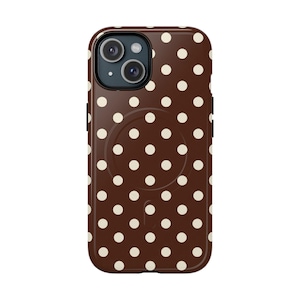 Peut inclure: Coque de téléphone marron à pois blancs. L'étui présente une indentation circulaire au dos et une découpe pour l'appareil photo. L'étui est conçu pour un smartphone.