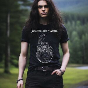 May include: A black t-shirt with a white graphic of an owl perched on a skull. The text "Grateful Not Hateful" is printed on the shirt.