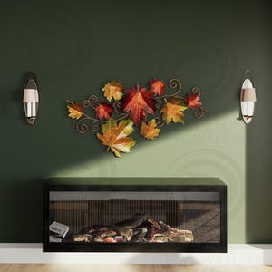 May include: Metal wall art depicting autumn leaves in red, orange, and yellow hues, attached to a decorative vine. The artwork is mounted on a dark green wall above a black fireplace. The fireplace is 150 cm wide.