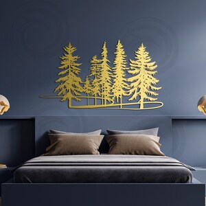 May include: Gold metal wall art featuring a silhouette of a forest with multiple pine trees. The art is mounted on a dark blue wall above a bed with brown pillows.