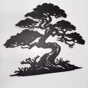 May include: Black metal silhouette of a bonsai tree with a thick trunk and intricate branches. The tree is set against a white background.