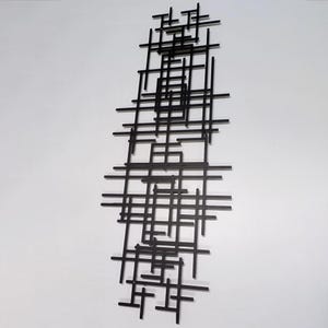 May include: Black metal wall sculpture with a geometric design of intersecting lines and squares.