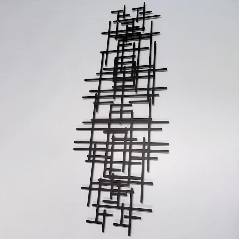 May include: Black metal wall sculpture with a geometric design of intersecting lines and squares.