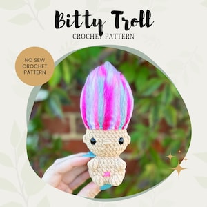 May include: A crocheted troll doll with pink, blue, and white yarn hair. The doll is holding a pink star in its hand. The doll is sitting on a hand. The image has the text "Bitty Troll Crochet Pattern" and "No Sew Crochet Pattern".