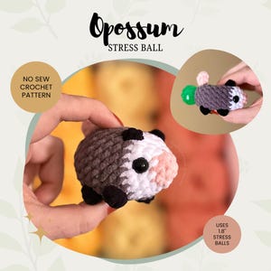 Puede incluir: Un balón antiestrés de crochet gris y blanco con forma de zarigüeya con ojos y nariz negros. La zarigüeya está sosteniendo un balón antiestrés verde en su boca. El texto "NO SEW CROCHET PATTERN" y "USES 1.8" STRESS BALLS" es visible en la imagen.