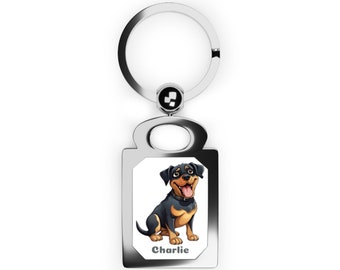 Op de afbeelding: Zilveren sleutelhanger met een rechthoekig label met een cartoon Rottweiler-hond met de naam "Charlie" eronder gedrukt.