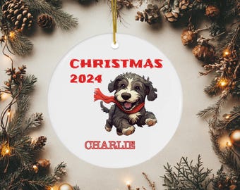 Puede incluir: Adorno de Navidad de cerámica blanca con un perro de dibujos animados que lleva una bufanda roja. El adorno dice "Navidad 2024" y "Charlie".