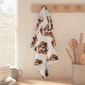 May include: White kitchen towel with a repeating pattern of a beagle dog wearing a Santa hat. The dog is looking to the right and has a red nose and brown eyes.