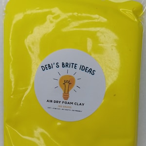 May include: A package of bright yellow air dry foam clay. The package has a round sticker with the text "DEBI'S BRITE IDEAS" and "AIR DRY FOAM CLAY". The sticker also says "100 GRAMS" and "SOFT - STRETCHY - DIY CRAFTS - KID FRIENDLY".