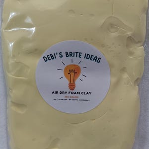 May include: A yellow air dry foam clay in a clear plastic bag with a white label that says "DEBI'S BRITE IDEAS" with a lightbulb icon and the text "AIR DRY FOAM CLAY 100 GRAMS SOFT-STRETCHY-DIY CRAFTS-KID FRIENDLY"