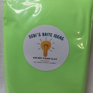 May include: A package of bright green air dry foam clay. The package has a circular label with the text "Debi's Brite Ideas" and an illustration of a lightbulb. The label also states "Air Dry Foam Clay 100 grams".
