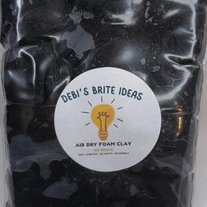 May include: A clear plastic bag filled with black air dry foam clay. A white circular label features the text "Debi's Brite Ideas" and "Air Dry Foam Clay" with a lightbulb graphic. The label also states the clay is soft, stretchy, DIY crafts, and kid friendly.