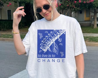 May include: White t-shirt with a blue graphic of a plant with the text "to live is to CHANGE" printed on it.