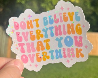 May include: A white sticker with a rainbow glitter background and the text "Don't believe everything that you overthink" in a colorful, retro font.