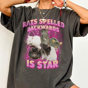 May include: A dark gray t-shirt with a graphic print of rats and the text "Rats spelled backwards is star" in pink.