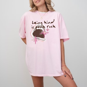 Comfort Colors 1717 Shirt
Color: Blossom (light pink)
Graphic: open screaming mouth in a retro halftone print, surrounded by pink stars and starbursts, with the handwritten phrase “Being Kind is Punk Rock” above in brown lettering