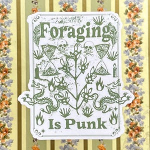 May include: A white sticker with green text and illustrations. The text reads "Foraging is Punk". The illustrations include skulls, a plant, and a dragon.