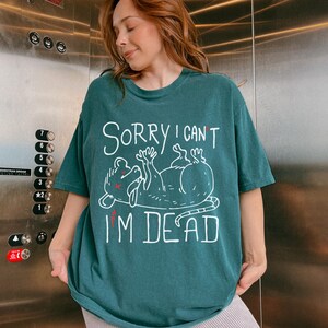 Text: "Sorry I Can't I'm Dead" Possum Sketch, Tongue Out with X Eyes Teal, Blue/Green Shirt, White Text and Outline, Funny Meme Tee, Introverted, Anxiety Opossums, Rat Shirt, Trashcore