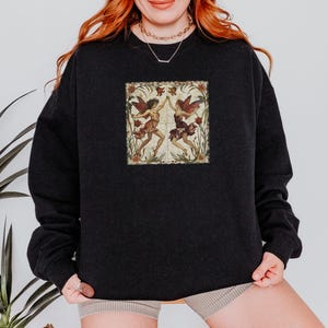 May include: Black sweatshirt with a vintage illustration of two fairies dancing in a floral frame.