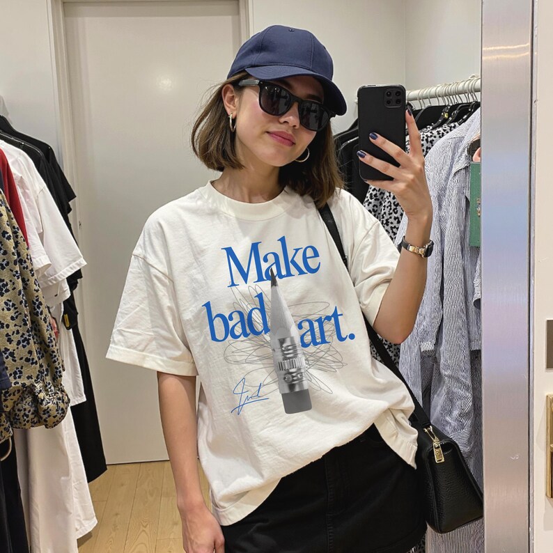Comfort Colors 1717 Shirt
Color: White
Graphic: Bold blue text that reads ‘Make bad art' behind a pencil graphic, with scribble doodle lines in gray and a signature-style accent in bottom corner