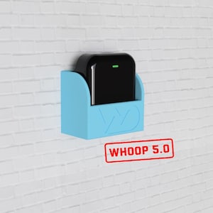May include: A black device with a green light is mounted in a light blue holder on a white brick wall. The holder has a stylized "W" design. The text "WHOOP 5.0" is stamped in red below the holder.