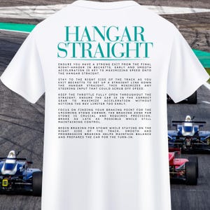 Könnte beinhalten: Weißes T-Shirt mit dem Text "HANGAR STRAIGHT" in Blau und Schwarz. Der Text darunter erklärt, wie man ein Rennwagen auf einer Rennstrecke fährt, mit Anweisungen für die Hangar Straight und die Stowe Corner.
