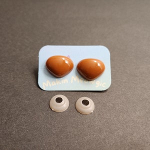 May include: Two brown plastic safety eyes with a white backing card that says "Makin' Magic".